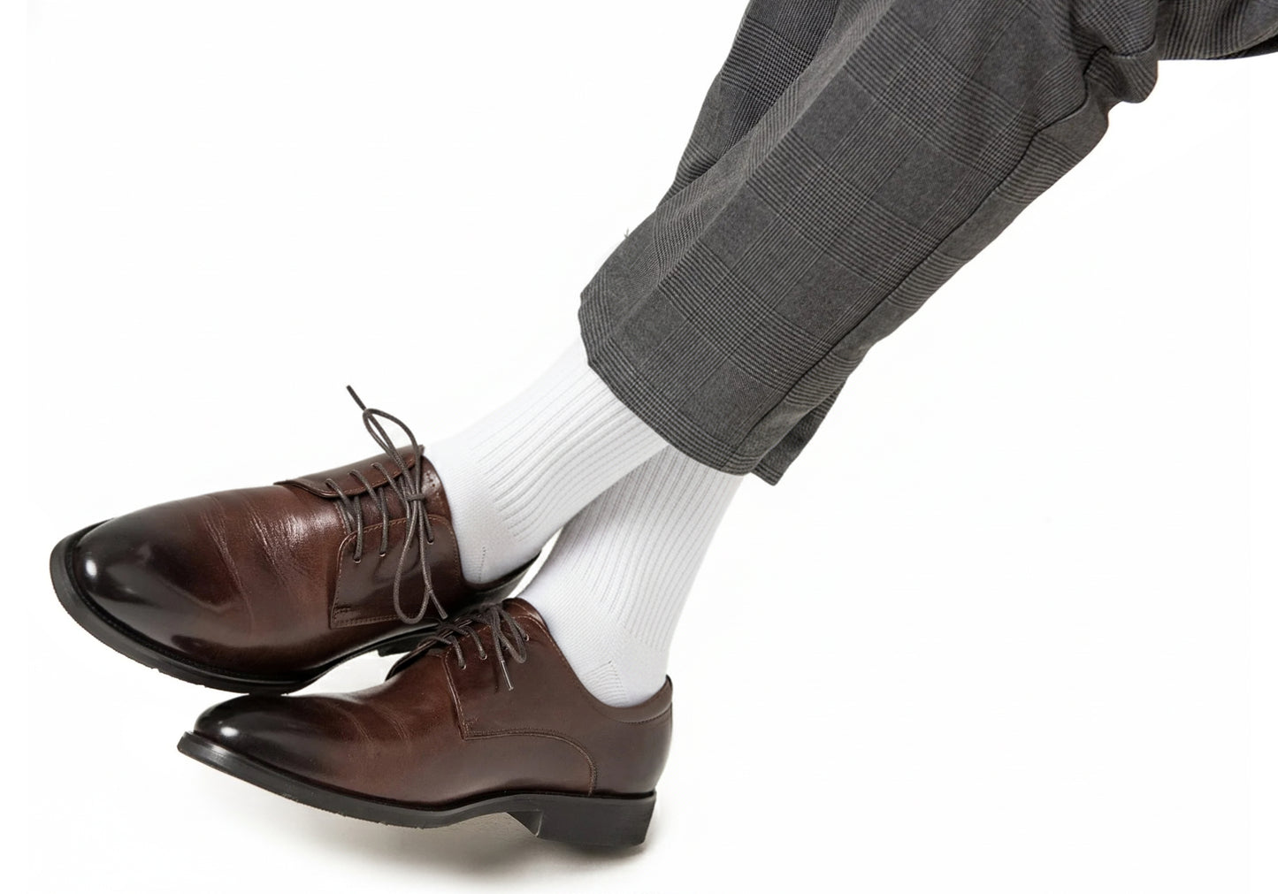 Person wearing AusCufflinks Socks in white (cotton blend formal), brown leather dress shoes, and gray plaid dress pants, legs crossed against a plain white background.