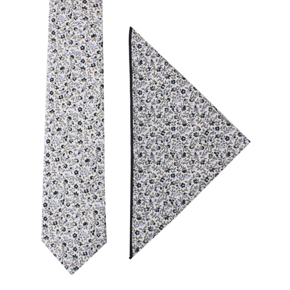 A sleek design featuring the Black Print Floral Cotton Skinny Tie & Pocket Square Set is laid out on a plain white background. The pattern consists of subtle florals in blue, white, and black.