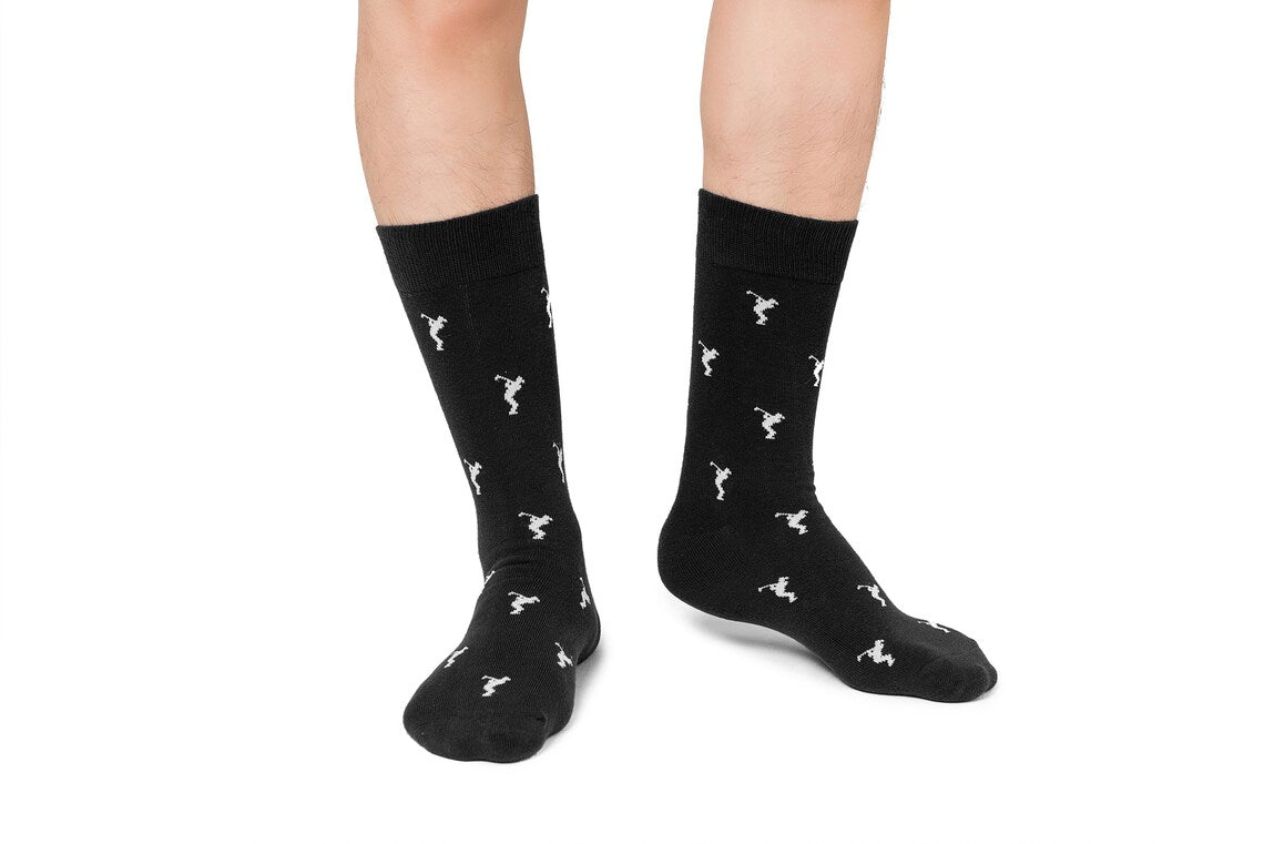Someone wearing Golf Swing Black Socks featuring a white dancer pattern, standing on a white background.