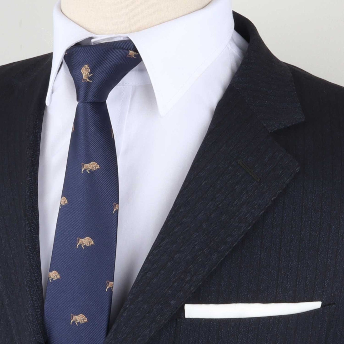 Close-up of a mannequin exuding power, draped in a dark pinstripe suit and white shirt, with a Bull Print Necktie adorned with lion motifs in dark blue. A white pocket square peeks from the breast pocket, symbolizing determination.