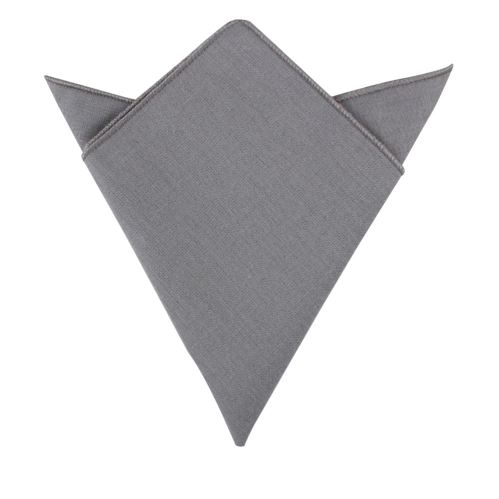 A versatile pocket square from the Grey Cotton Skinny Tie & Pocket Square Set, featuring pointed tips and neatly folded against a white background, adds a touch of style to any combo.