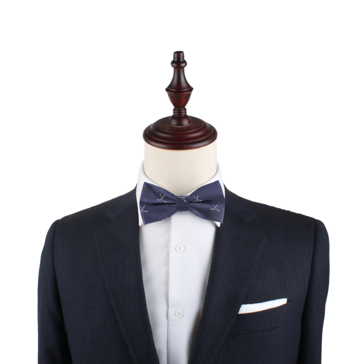 A headless mannequin in a dark suit and white shirt sports the Ice Hockey Cross Bow Tie with navy and white accents, plus a crisp white pocket square, adding a sporty flair against a white background.