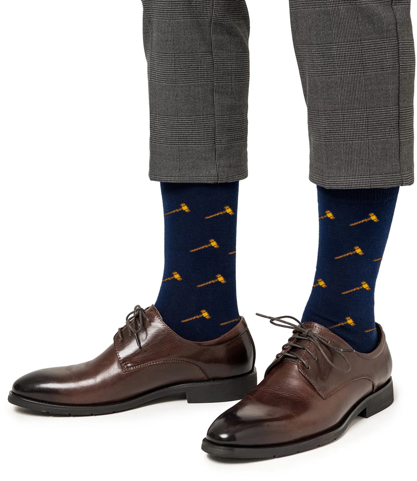 A person wearing gray plaid dress pants, brown dress shoes, and Gavel Socks in navy with a yellow gavel pattern.