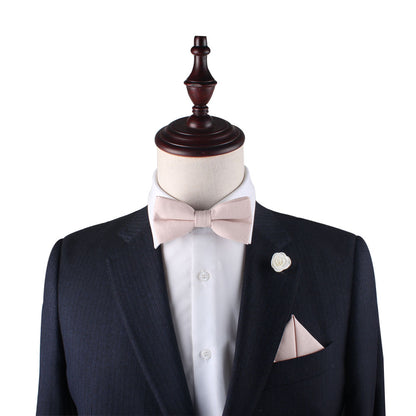 A man in a Cream Pink Cotton Bow Tie & Pocket Square set with a pink bow tie.