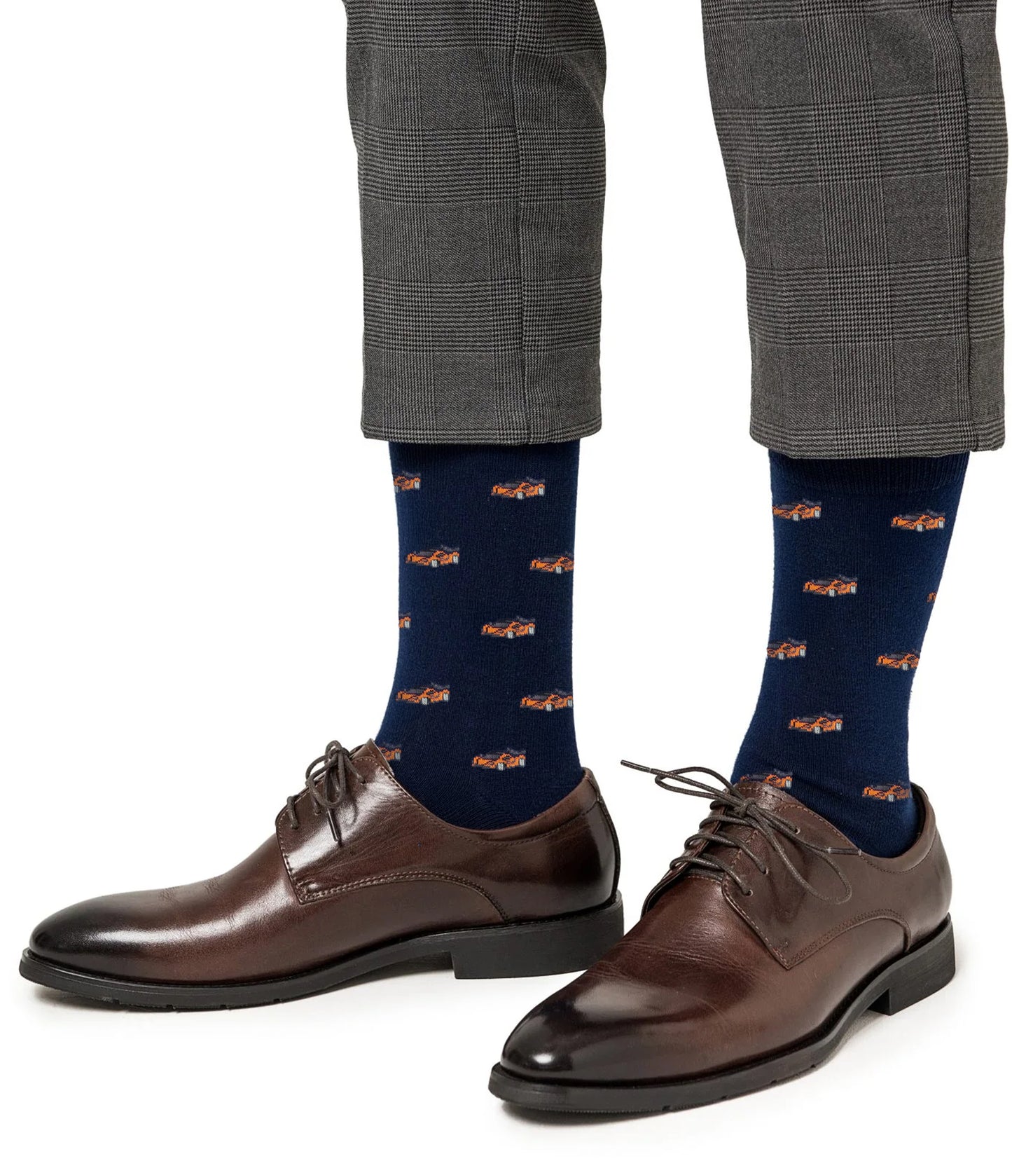A person wearing gray plaid pants, brown dress shoes, and Orange Race Car Socks—eye-catching socks adorned with vibrant race car graphics, ideal for any motorsport enthusiast.