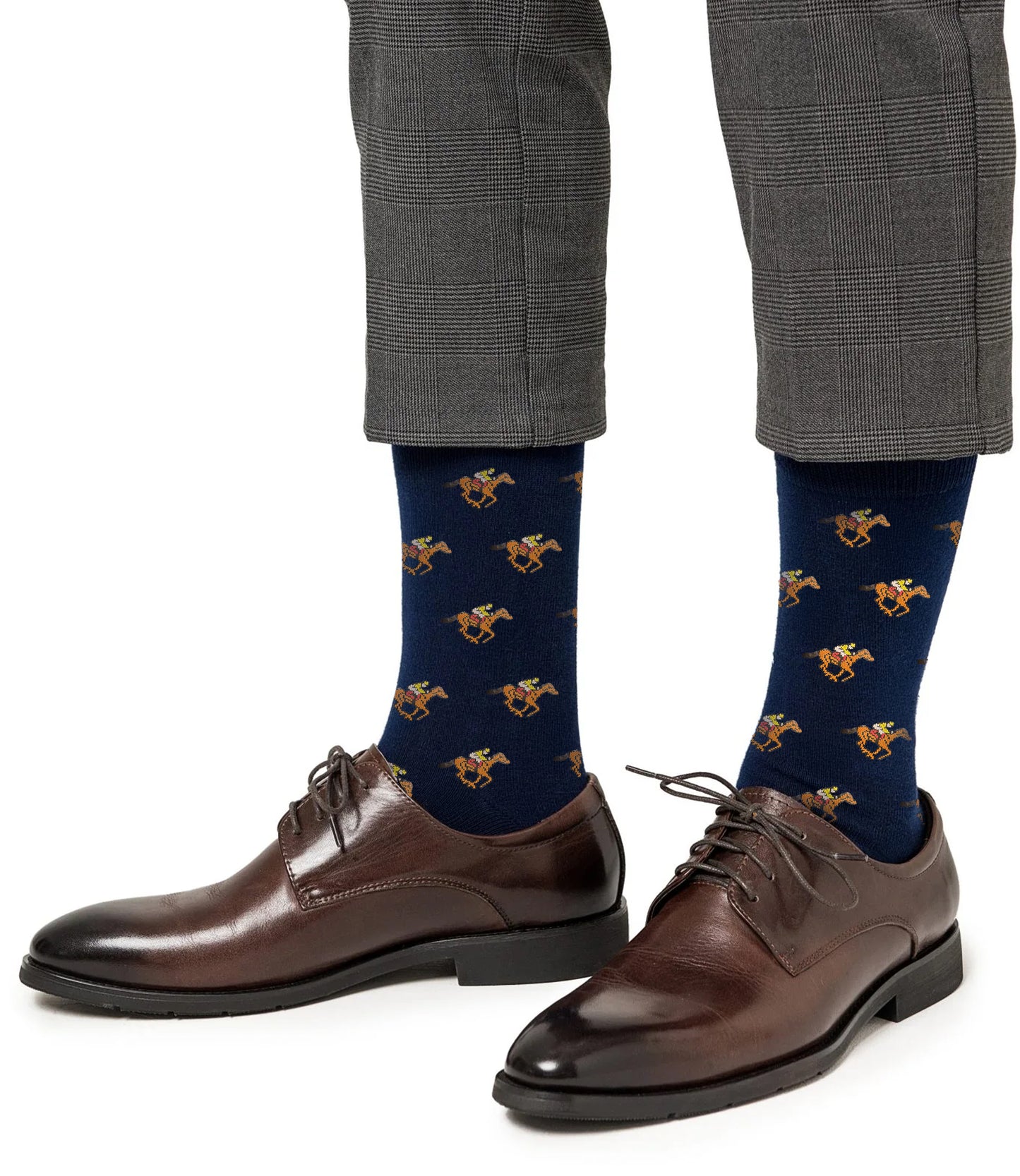 A person wearing gray plaid trousers, dark brown dress shoes, and Melbourne Race Horse Socks featuring a colorful pattern.