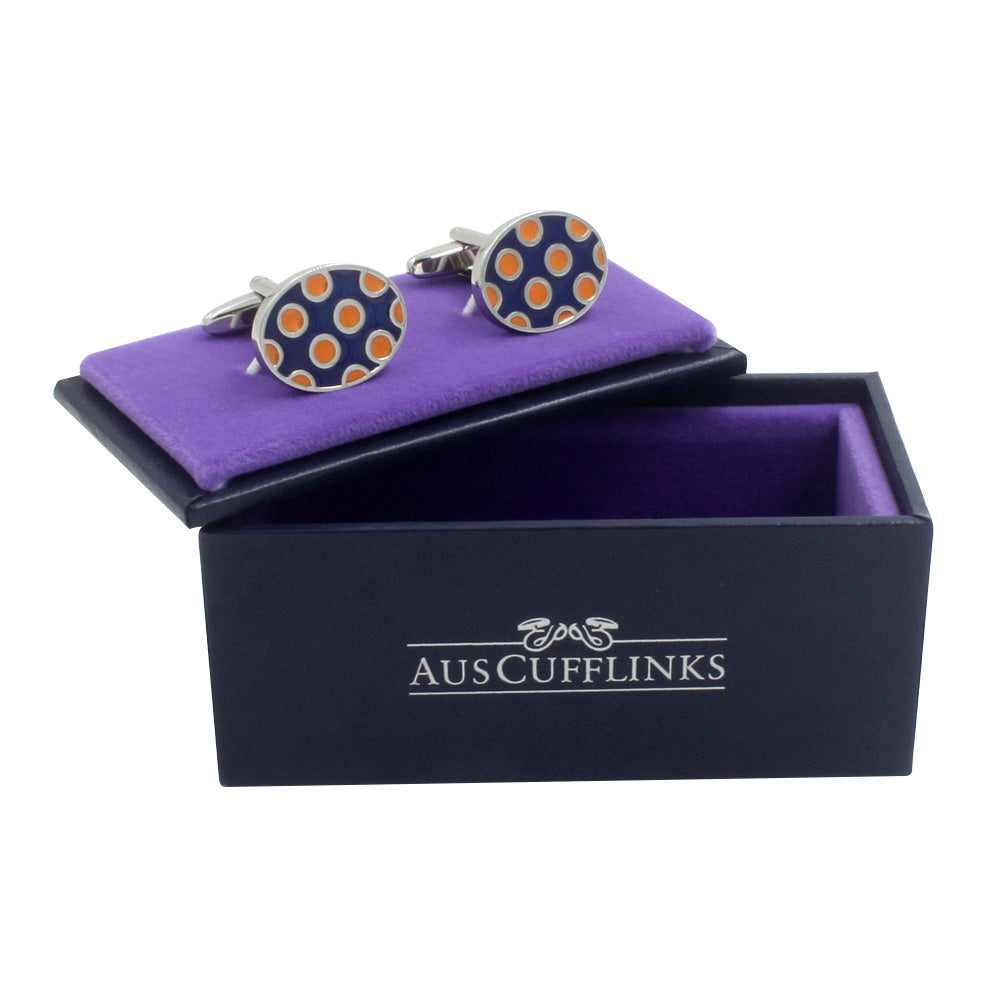 The "Ladybug Orange Navy Cufflinks" showcase an orange and blue dot design, elegantly displayed on purple fabric and nestled in a sleek black box marked "AusCufflinks," ideal for the modern gentleman.