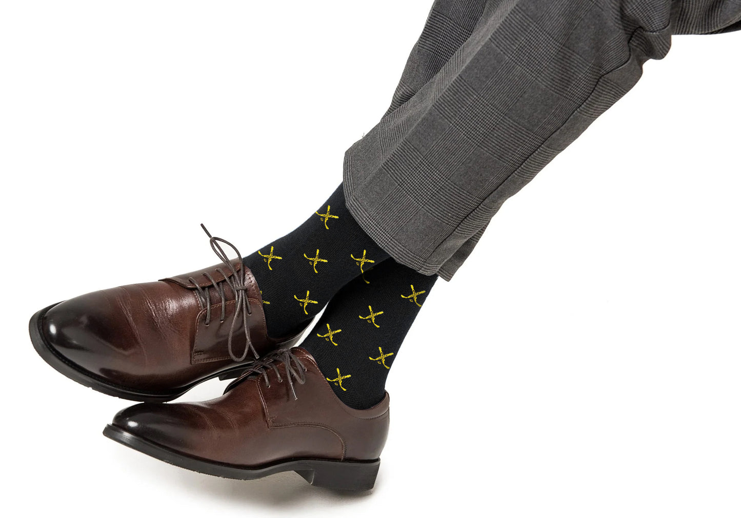 A person wearing brown dress shoes, gray plaid pants, and moisture-wicking black Yellow and Navy Ice Hockey Cross Socks.