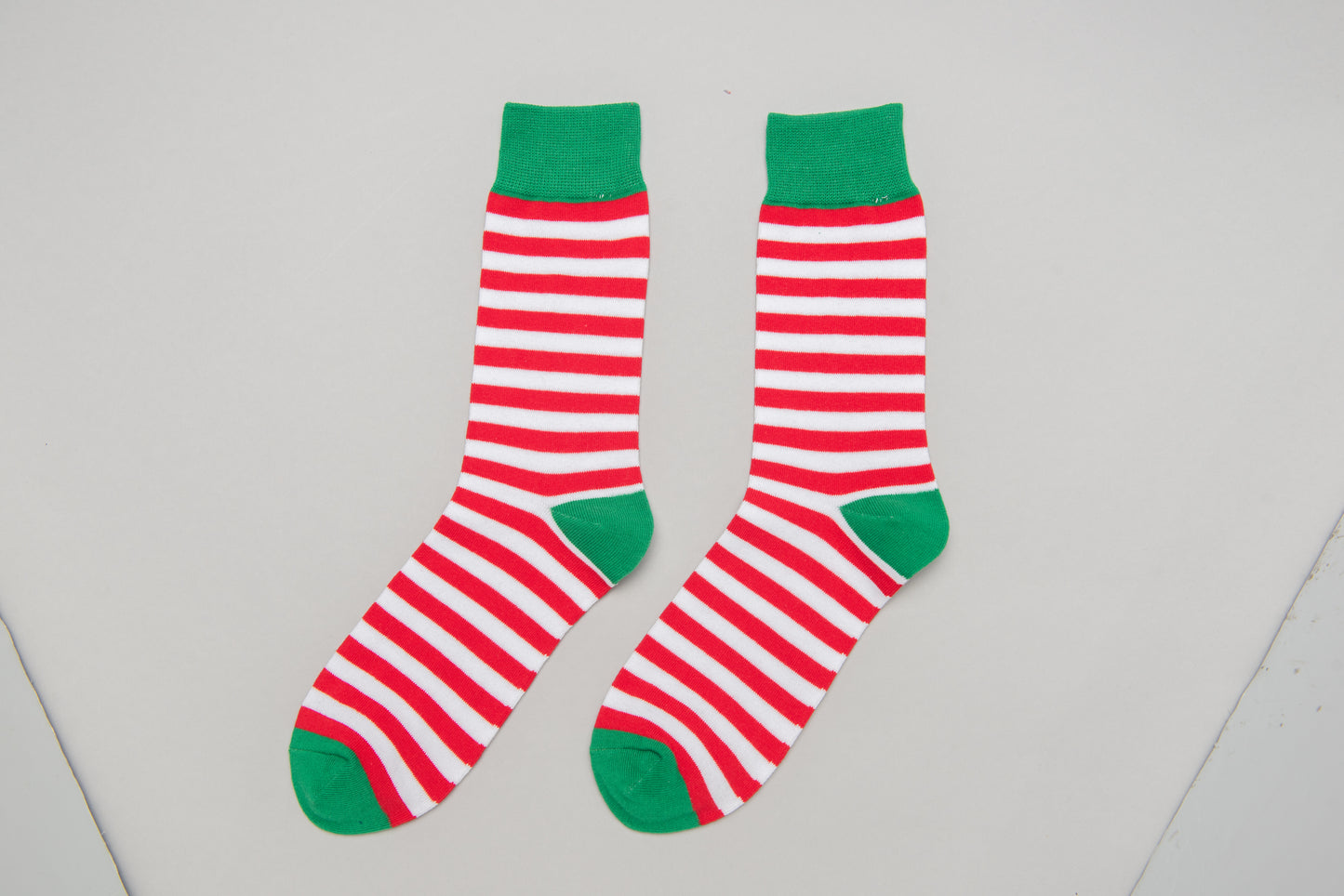 Fun Christmas-themed elf socks for men featuring red and white stripes on a festive design