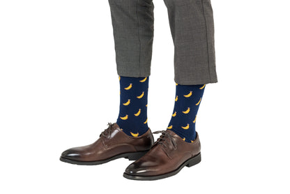 A pair of legs wearing brown shoes and blue Banana Socks.