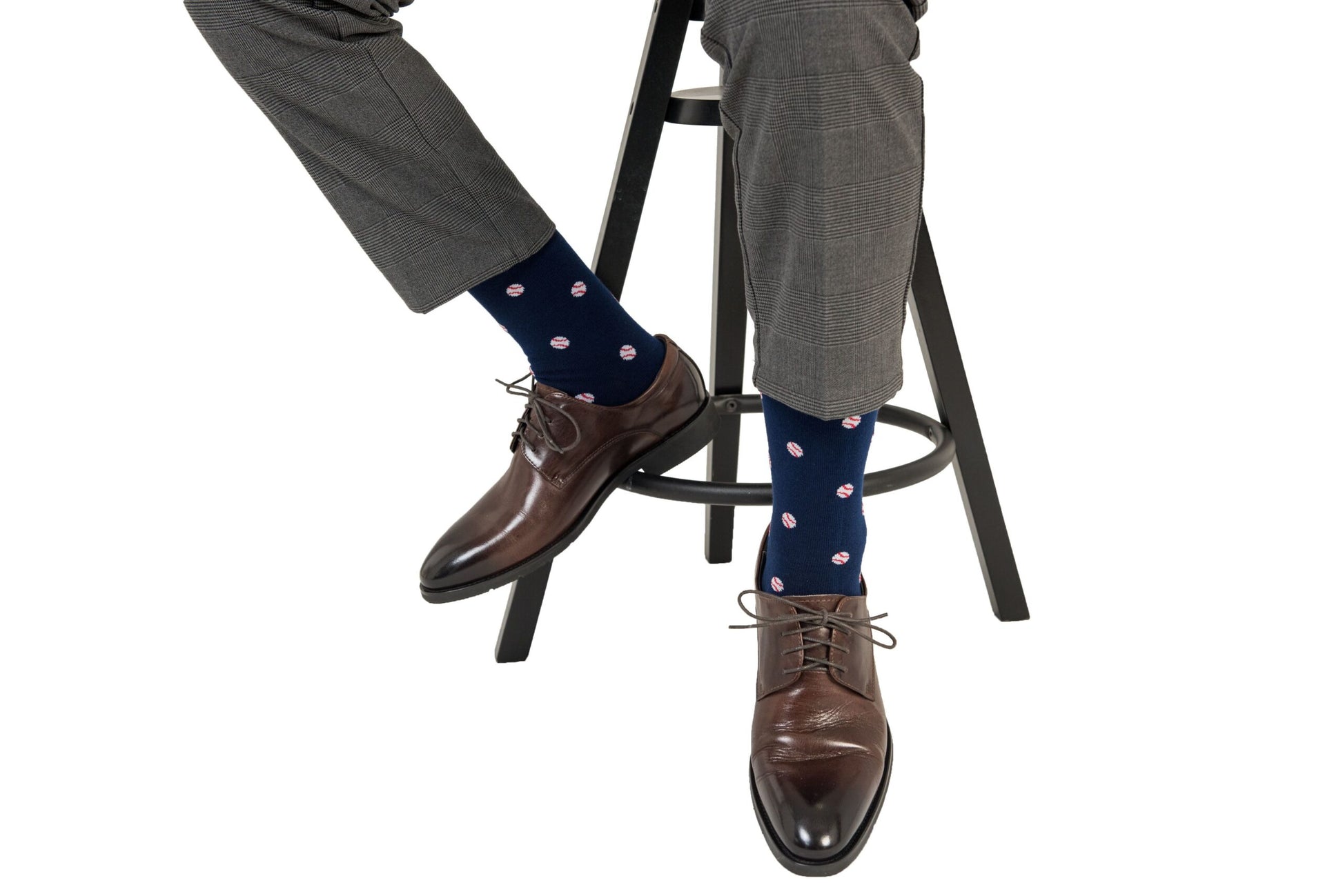 A man sitting on a stool wearing baseball socks.