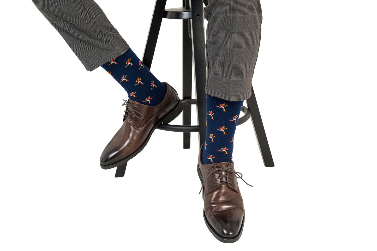 A man is sitting on a stool wearing a pair of Athletics Socks.