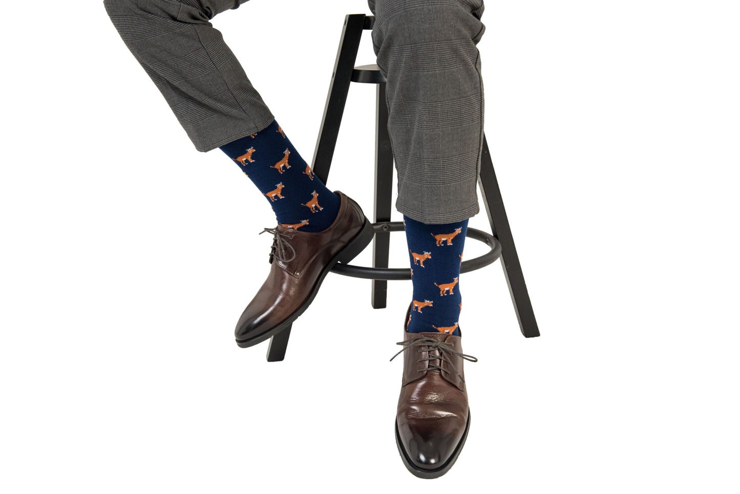 A man sitting on a stool wearing a pair of Goat Socks with foxes on them.