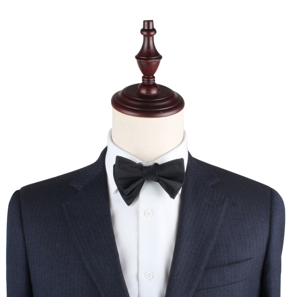 A classic Black Cotton Self Tie Bow Tie on a mannequin dummy.