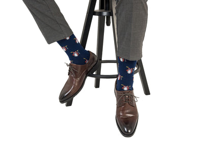 A man sitting on a stool wearing a pair of Drum Socks with a dog on them.