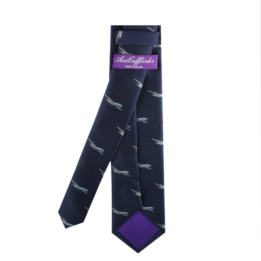 A navy blue Aeroplane Necktie with a subtle pattern of small white airplanes, exuding aeronautical charm. The inner label reads "Austedeylinks Australia," and the tip of the tie features a stylish purple fabric accent.