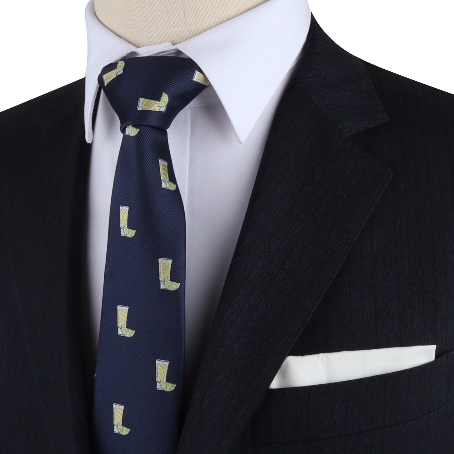 A close-up of a person wearing a black suit, white dress shirt, and the Tequila Skinny Tie featuring green boot prints that add zest to the ensemble. The dapper design is completed with a white pocket square in the suit’s breast pocket.