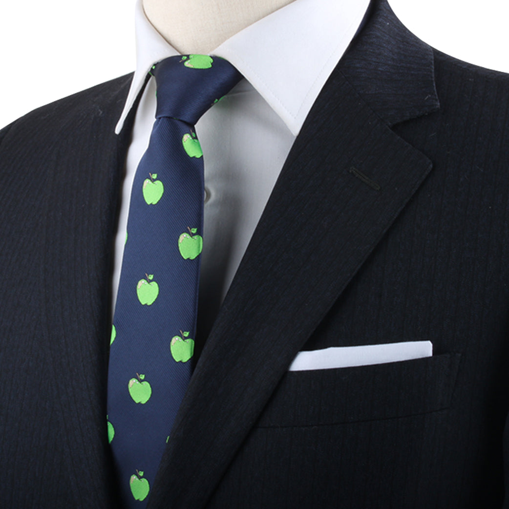 Mannequin dressed in a dark suit, white dress shirt, and an Apple Design Tie with green apple motifs, displaying a white pocket square, exudes modern style and natural freshness.