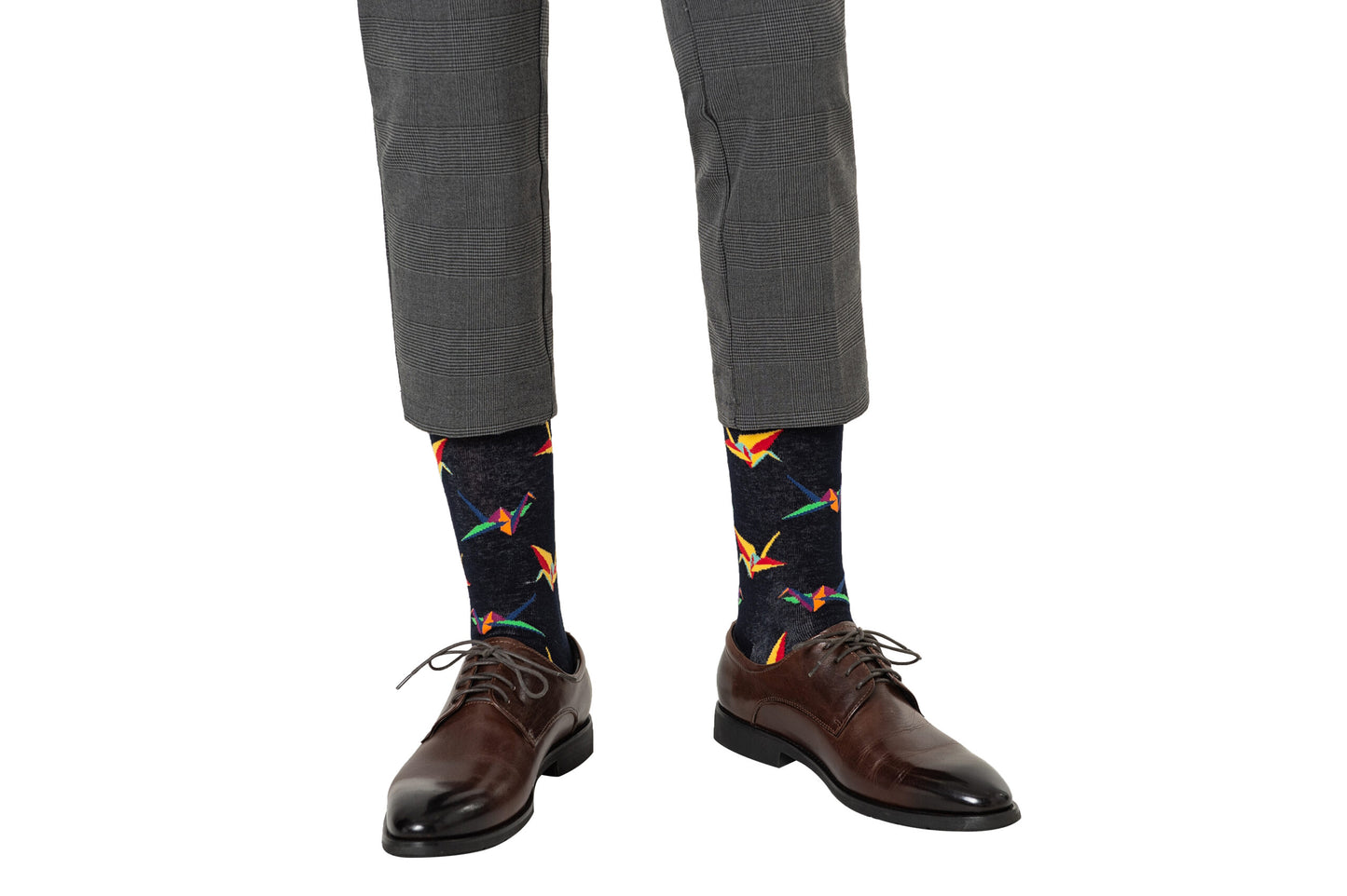 A person wearing gray plaid pants, Origami Socks with a colorful bird-pattern, and brown leather dress shoes that exude crafted comfort.