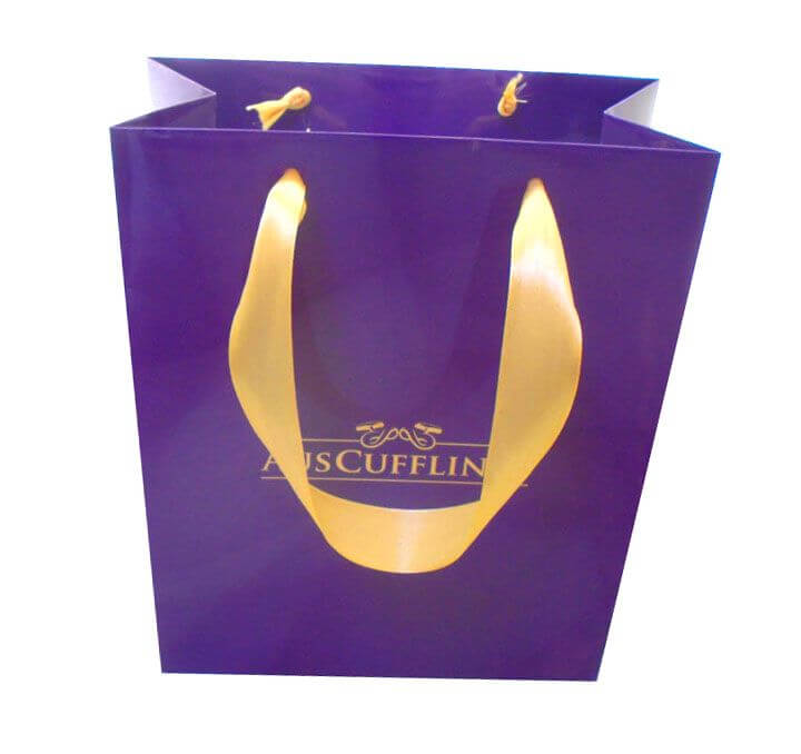 A Retail Bag featuring a purple paper design, yellow ribbon handles, and gold text branding on the front.