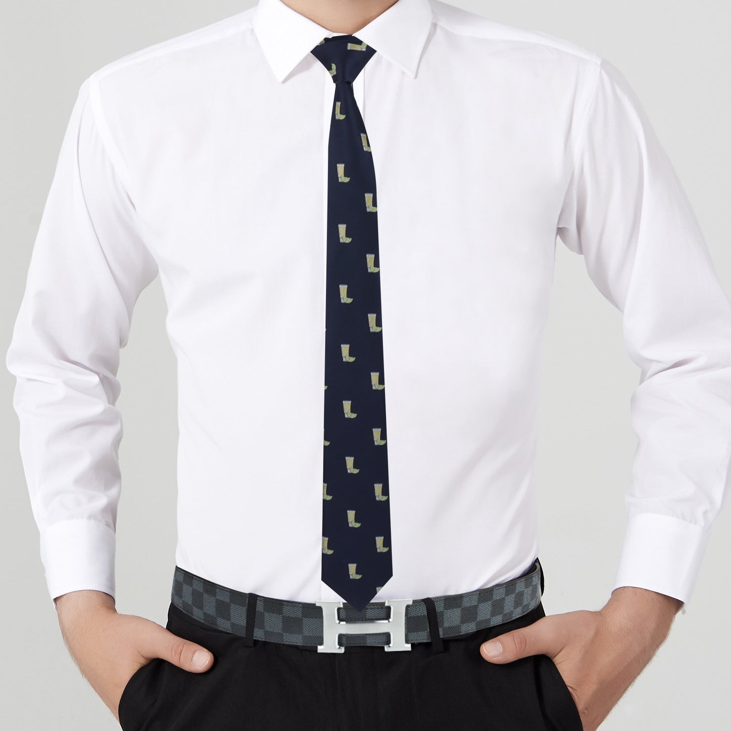 A person in a white dress shirt and dark pants sports the Tequila Skinny Tie and a checkered belt with a letter-shaped buckle, exuding a dapper design.