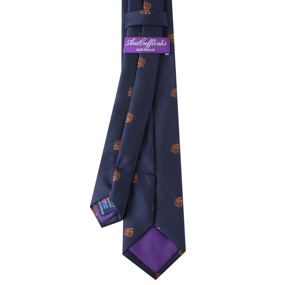 Introducing the Bear Print Tie, a tie with an untamed allure in navy blue, showcasing a pattern of small brown dog faces and finished with a sophisticated touch of purple lining.
