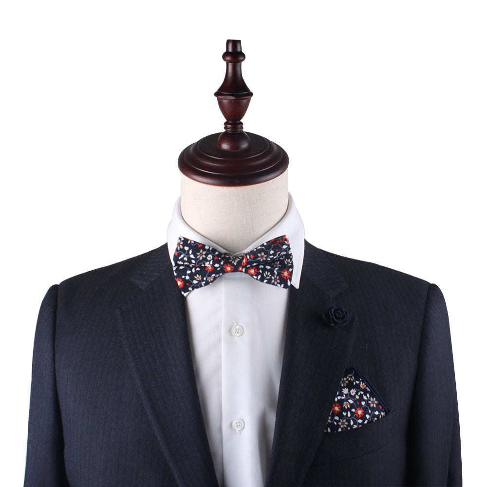 A suit with a bow tie and a Black Red Orange Amaryllis Floral pocket square on a mannequin.