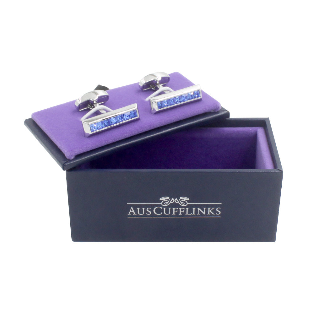 A pair of Blue Ice Cufflinks charm cufflinks in a purple box.