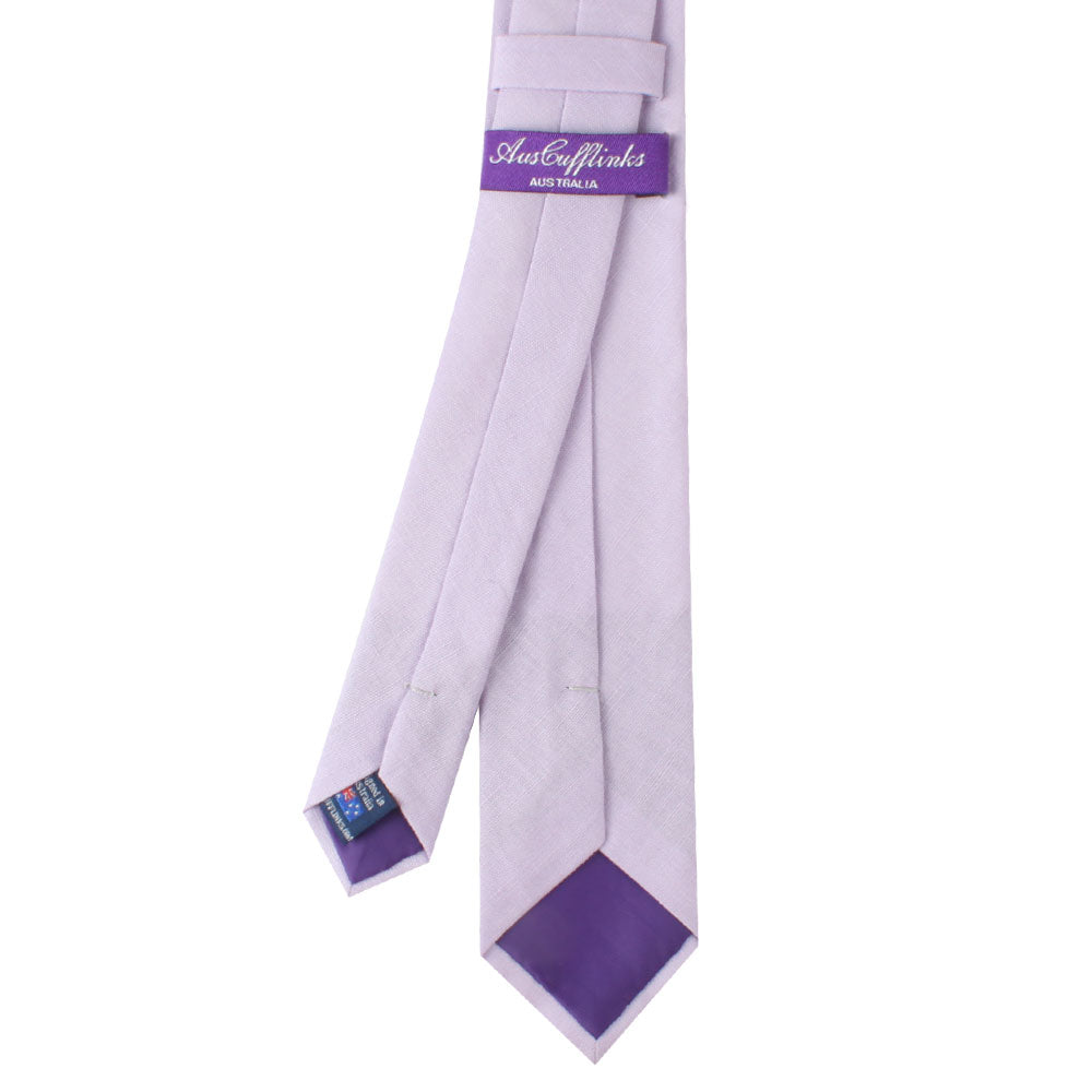 The Blush Purple Skinny Necktie and Pocket Square Set, a luxurious light lavender accessory with a purple label and accents, is laid flat on a white background, perfectly complementing any sophisticated ensemble.