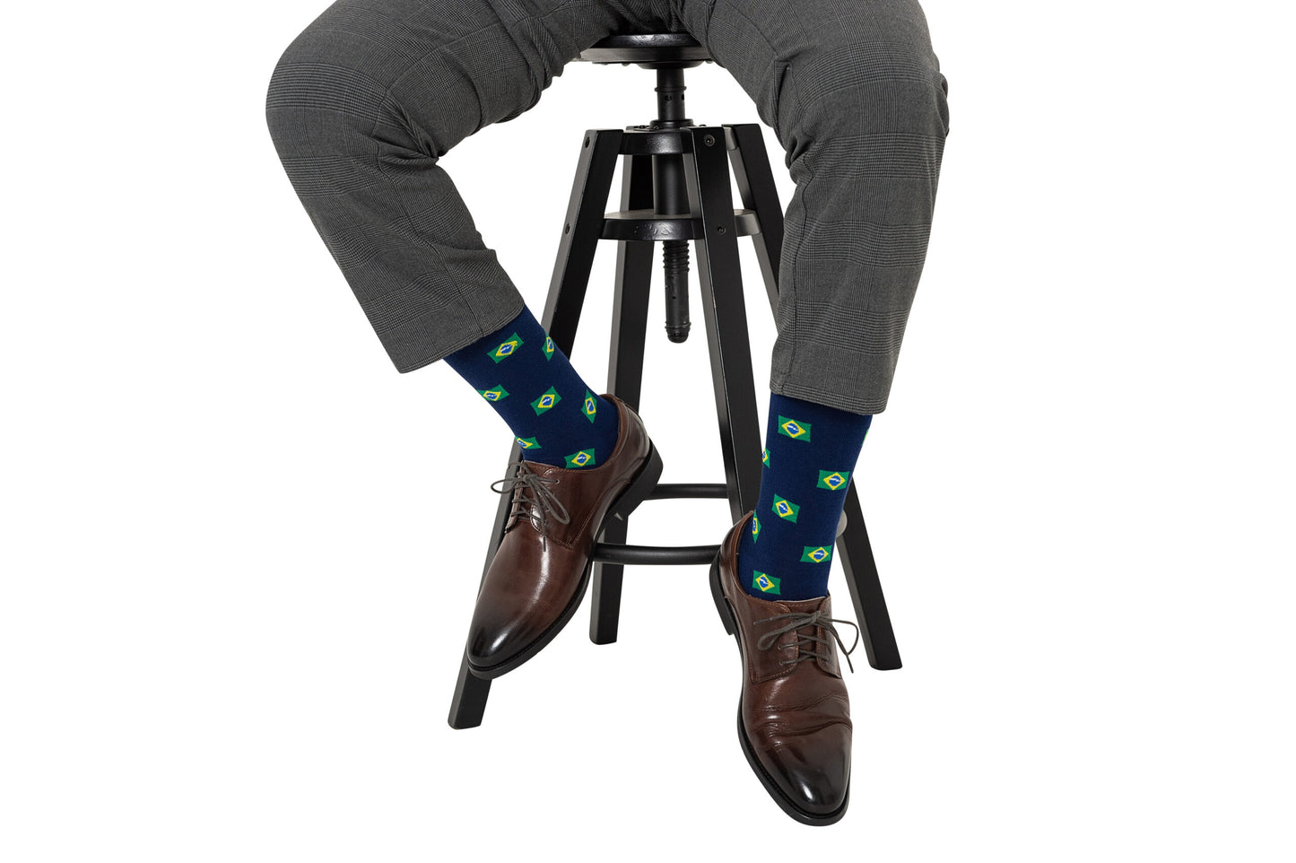 A man sitting on a stool wearing a pair of Brazil Flag Socks.