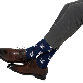 A pair of legs wearing brown shoes with blue socks and white Bunny Socks showcasing a playful collection of unique patterns.