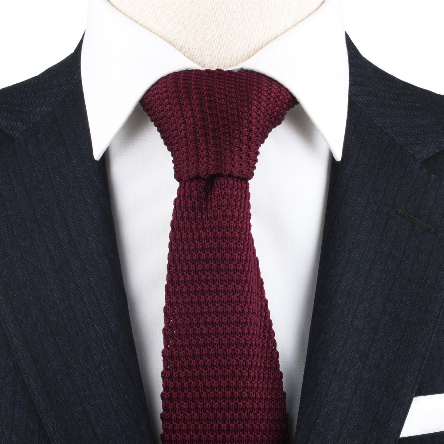 A close-up of a person wearing a dark pinstripe suit, a white dress shirt, and the Maroon Knitted Skinny Tie, exuding cozy elegance with the warm hues of the ensemble.