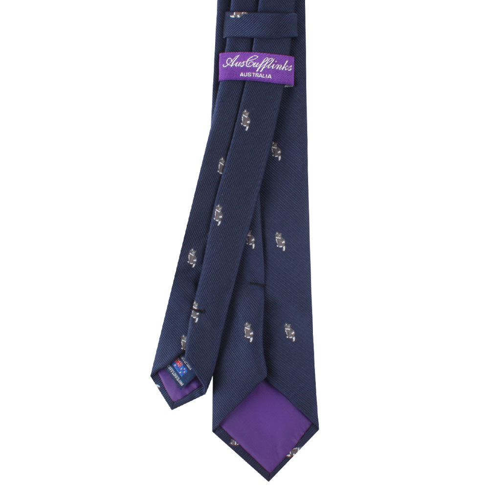 A Cat Patterned Tie with small white dog motifs and purple lining on the inner tip, exuding charm and sophistication, featuring an "Auburn Wings Australia" label and brand tag. Perfect for cat lovers who also appreciate unique designs.