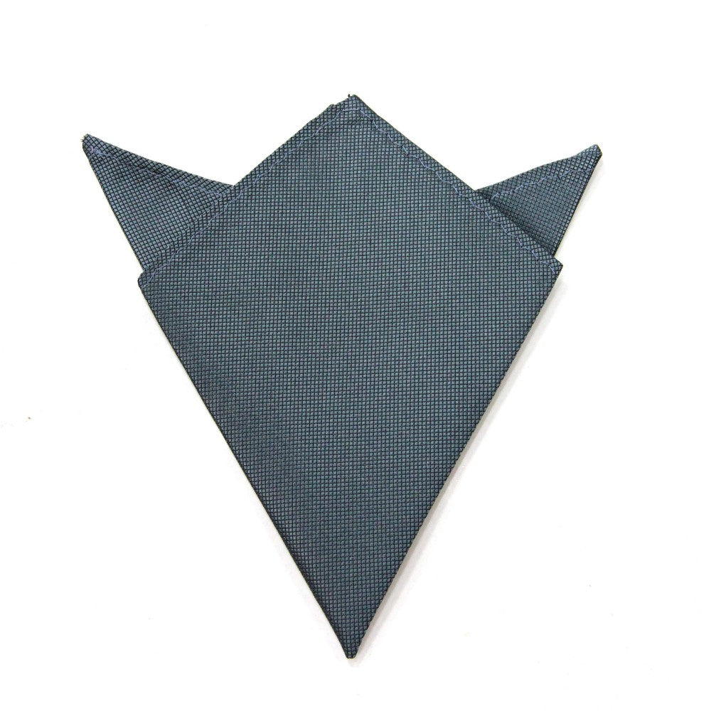 The Grey Pocket Square, folded into a geometric shape resembling a fox head with pointy ears, made from dark blue textured fabric, exudes modern elegance and adds a sophisticated touch to any ensemble.