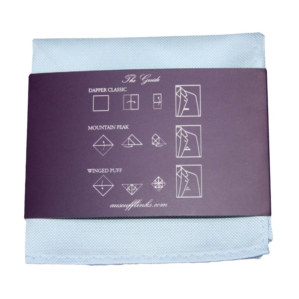 The Light Blue Pocket Square has a classic look with a dark label showing diagrams and instructions for three folding styles: Dapper Classic, Mountain Peak, and Winged Puff. This stylish accessory effortlessly elevates your appearance.