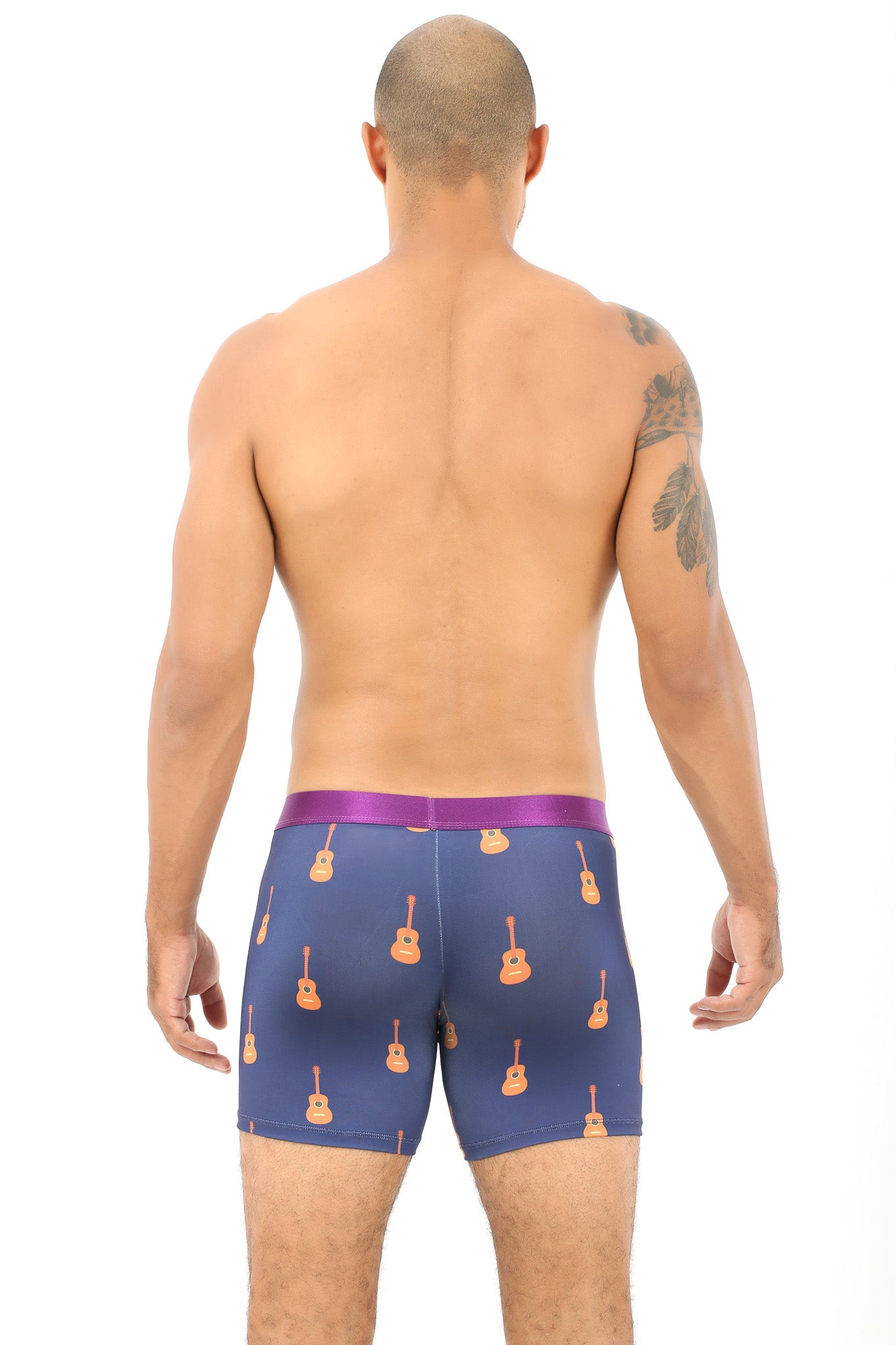 A man stands with his back to the camera, wearing Guitar Underwear — blue boxer briefs featuring guitar patterns that provide a perfect blend of comfort and style.