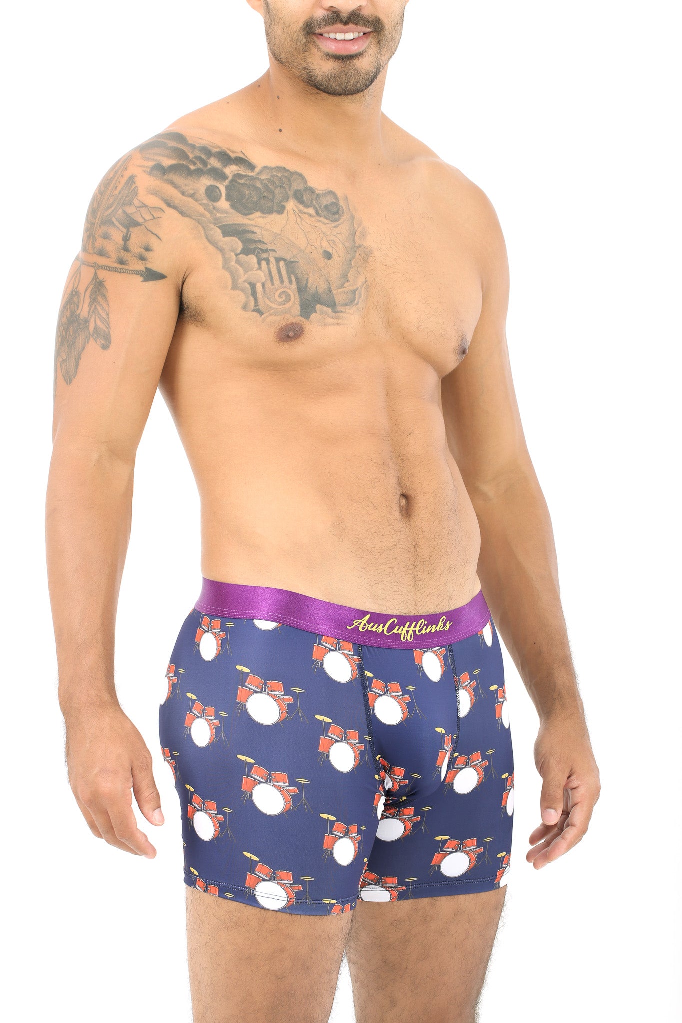 A person wearing Drums Underwear, featuring vibrant drum set patterns, embraces a rhythm of comfort, showcasing tattoos on their upper body.
