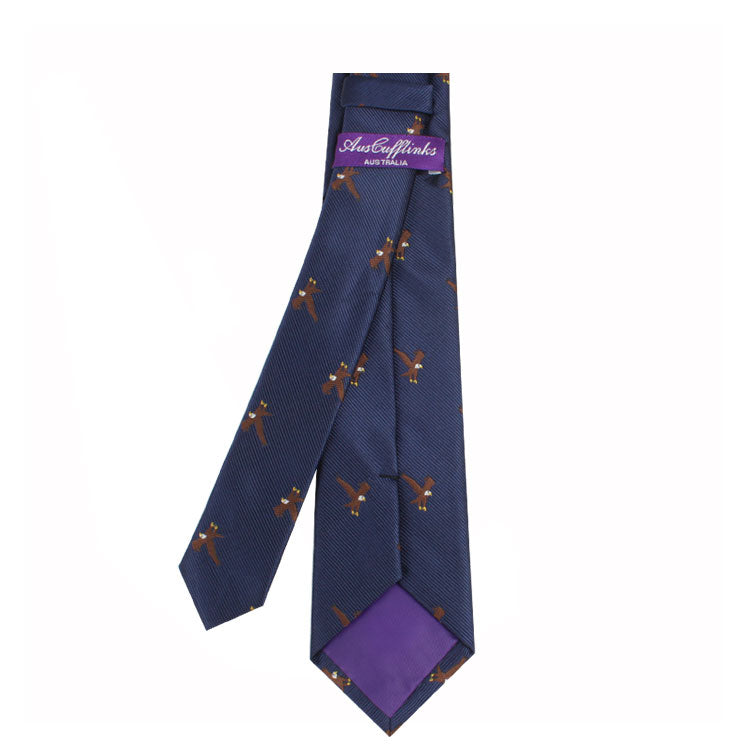 The Eagle Bird Skinny Tie is a navy blue necktie with brown otter patterns, ideal for formal business attire, and features a purple "Arden Gyllenhall" label on the back.