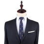 A mannequin dressed in a dark suit with a white dress shirt and an Eiffel Tower Slim Tie exudes Parisian elegance. A white pocket square is neatly tucked into the jacket's breast pocket, completing the sophisticated woven look.