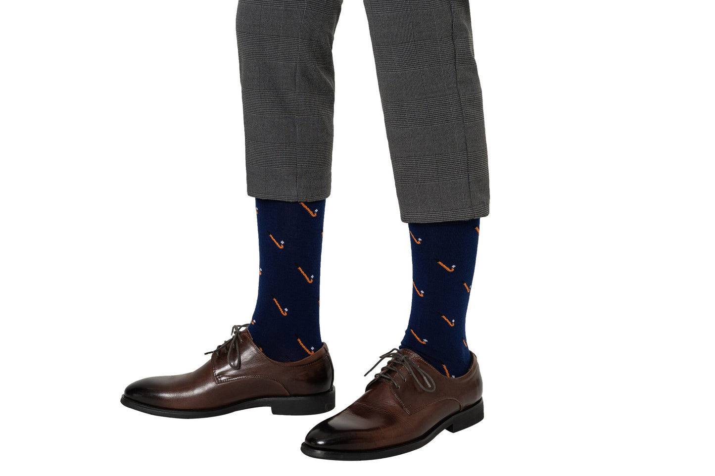 A person wearing gray plaid pants, Field Hockey Socks in moisture-wicking navy blue with a small pattern, and brown dress shoes is shown from the knee down against a white background.