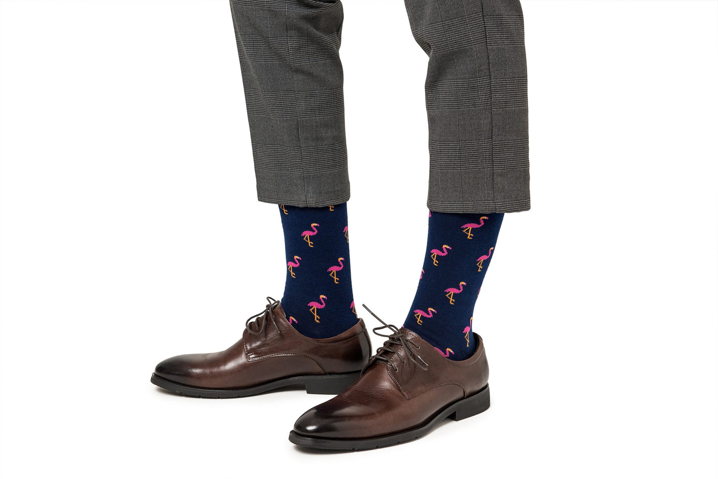 A person wearing gray plaid pants, from their whimsical sock collection Pink Flamingo Socks, and brown leather dress shoes.