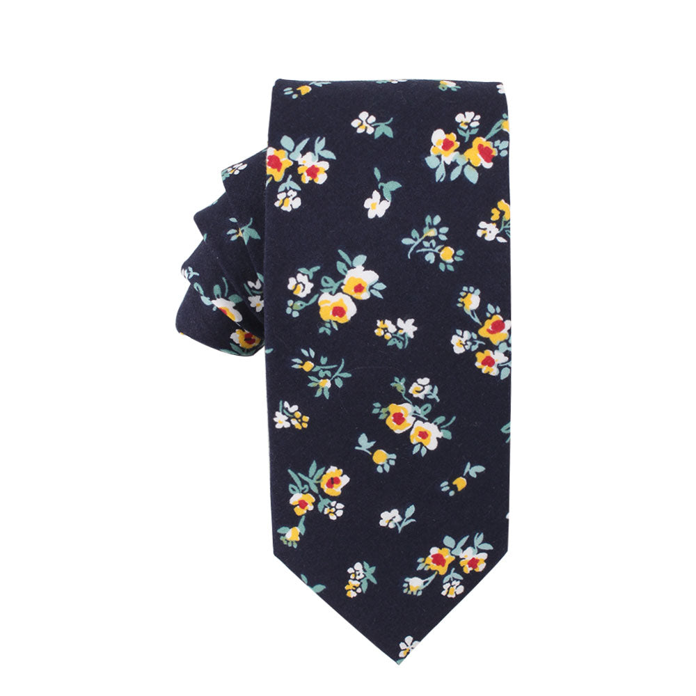 The Floral Navy Yellow Skinny Cotton Tie and Pocket Square features a deep blue hue adorned with golden blossoms, red flowers, and is beautifully accented by lush green leaves.