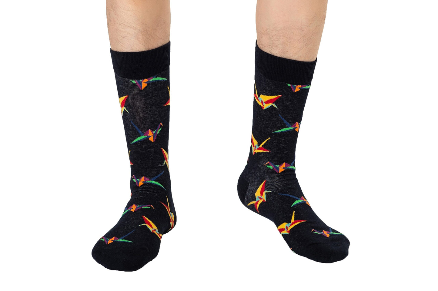 Individual presenting Origami Socks, featuring black fabric adorned with vibrant geometric patterns, combining folded finesse with expertly crafted comfort.