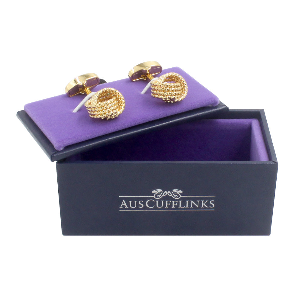 The Gold Knot Premium Cufflinks, featuring a luxury woven design, sit elegantly on a purple cushion inside an open black box labeled "AUSCUFFLINKS," perfect for the discerning gentleman.