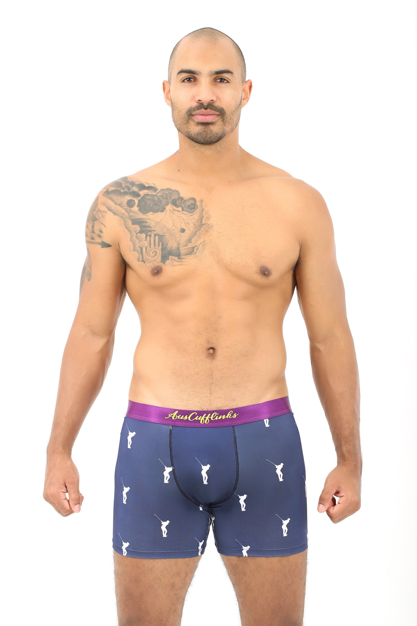 A man with a tattoo on his shoulder is modeling navy blue Golf Swing Boxer, featuring a purple waistband with "Two Cocks" written in cursive. Designed for ultimate comfort, the boxer briefs boast a pattern of small white rooster logos. Pair them with your favorite tee for an effortlessly stylish look.