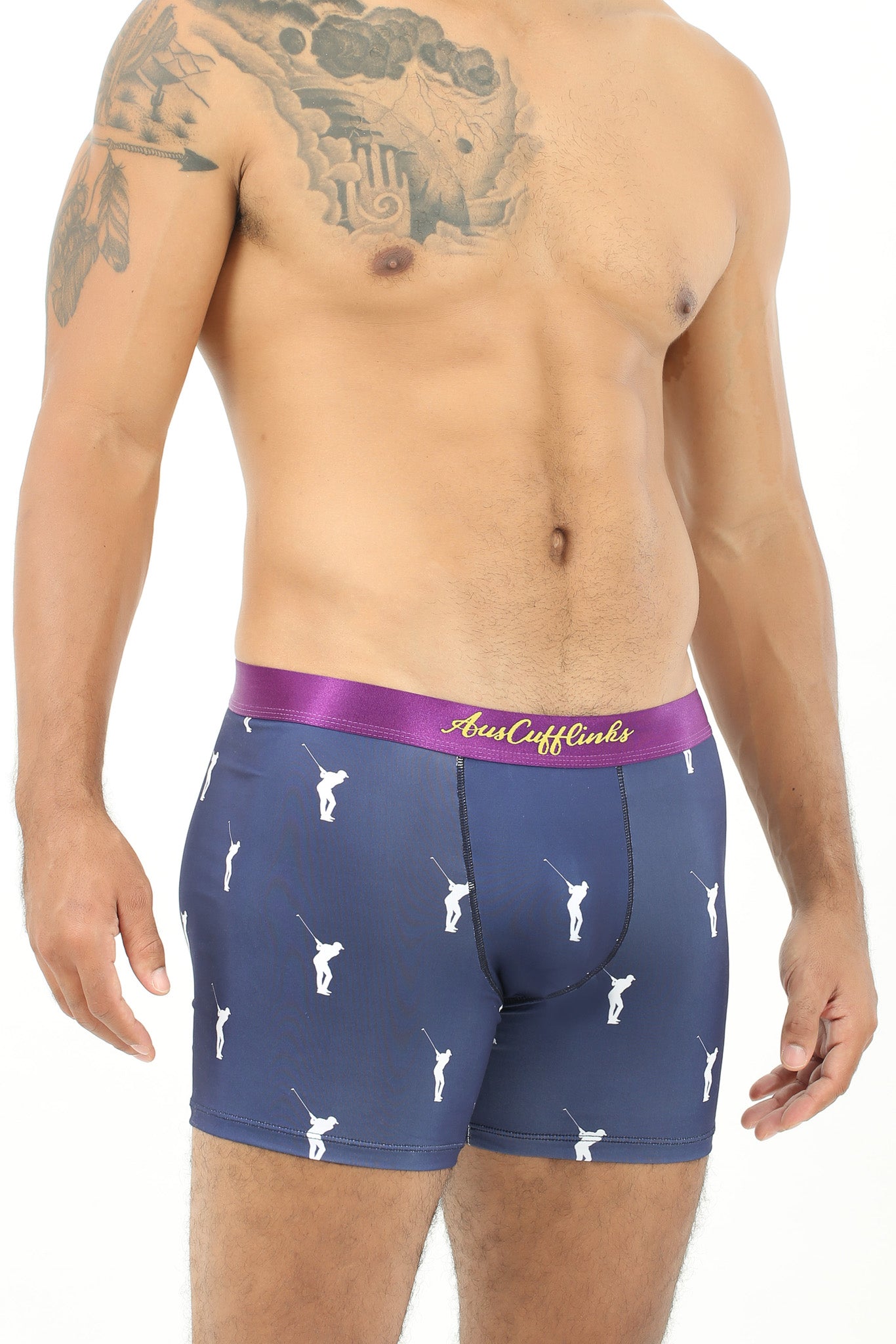 A man with tattooed arms models the Golf Swing Underwear, featuring dark blue boxer briefs with a purple waistband and white golfer prints, perfectly showcasing the ultimate drive for comfort.