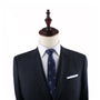 A mannequin exudes vineyard sophistication, wearing a dark suit with a white shirt and the Grapes Slim Tie featuring a small pattern.