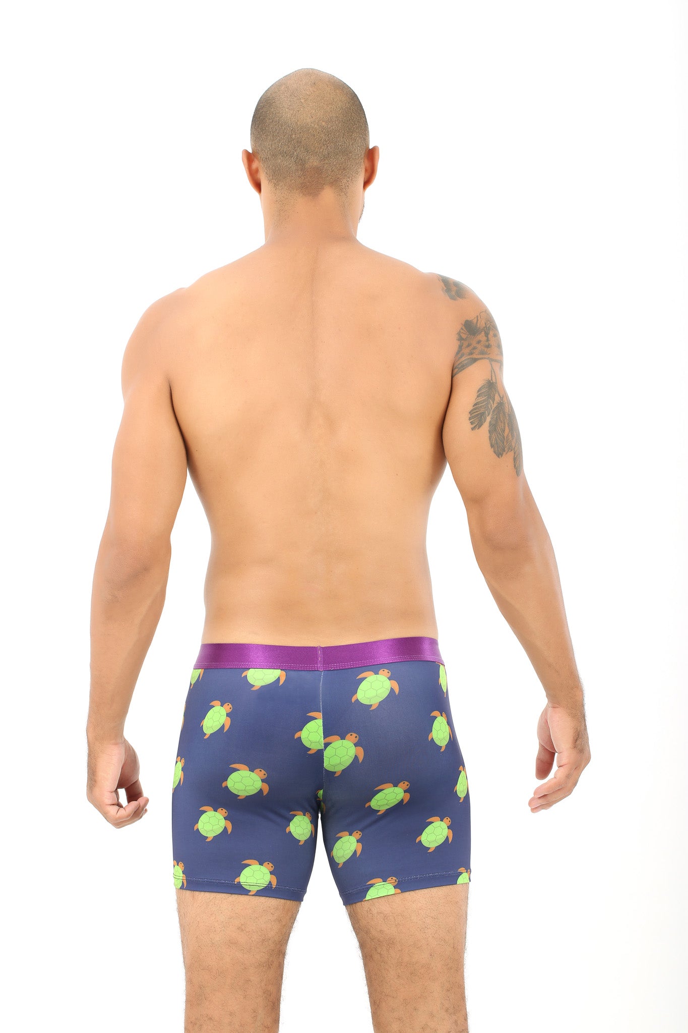 A man with a shaved head confidently displays his back, exuding style in Green Turtle Print Underwear that embodies slow-paced snugness.