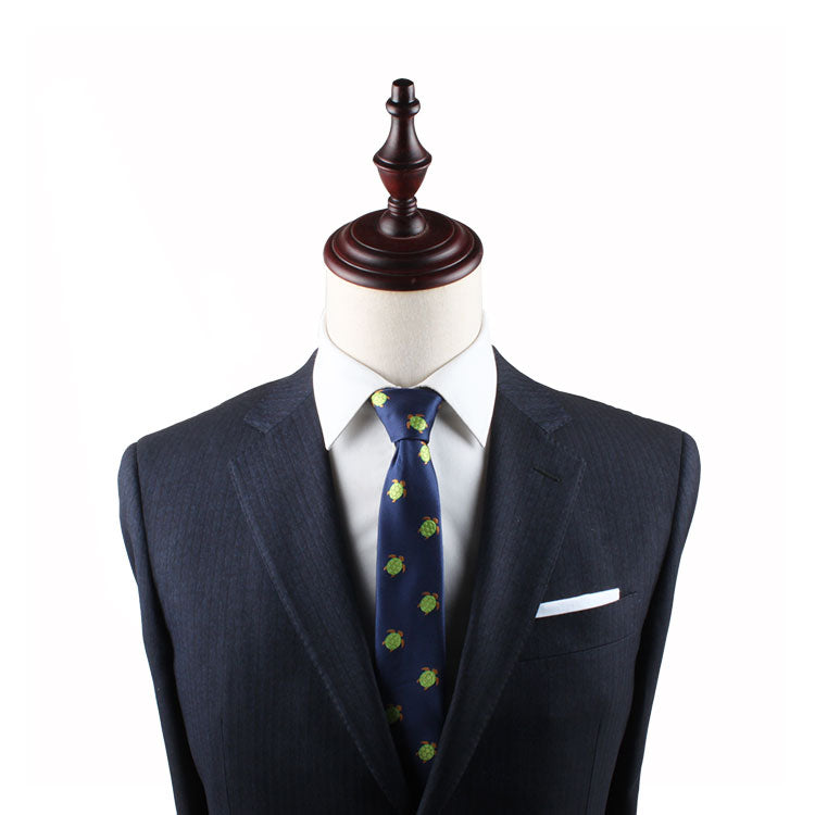 A mannequin dressed in a dark suit, Green Turtle Slim Tie, and white pocket square exuding natural elegance against a plain background.