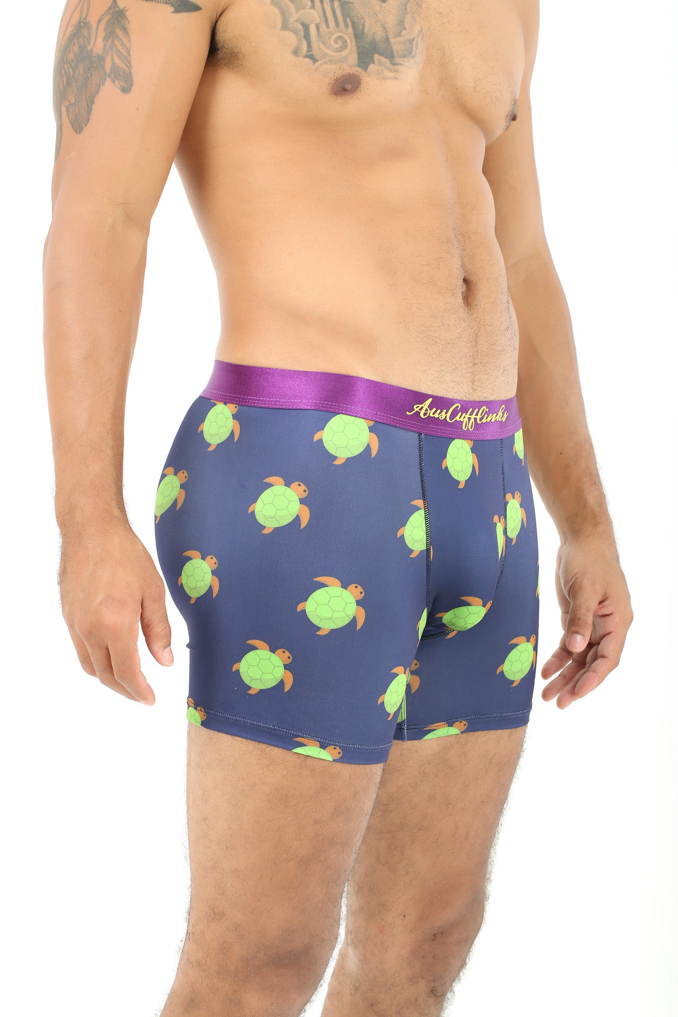 A person relishing the leisurely comfort of Green Turtle Underwear, featuring a blue hue with a charming turtle pattern and complemented by a purple waistband.